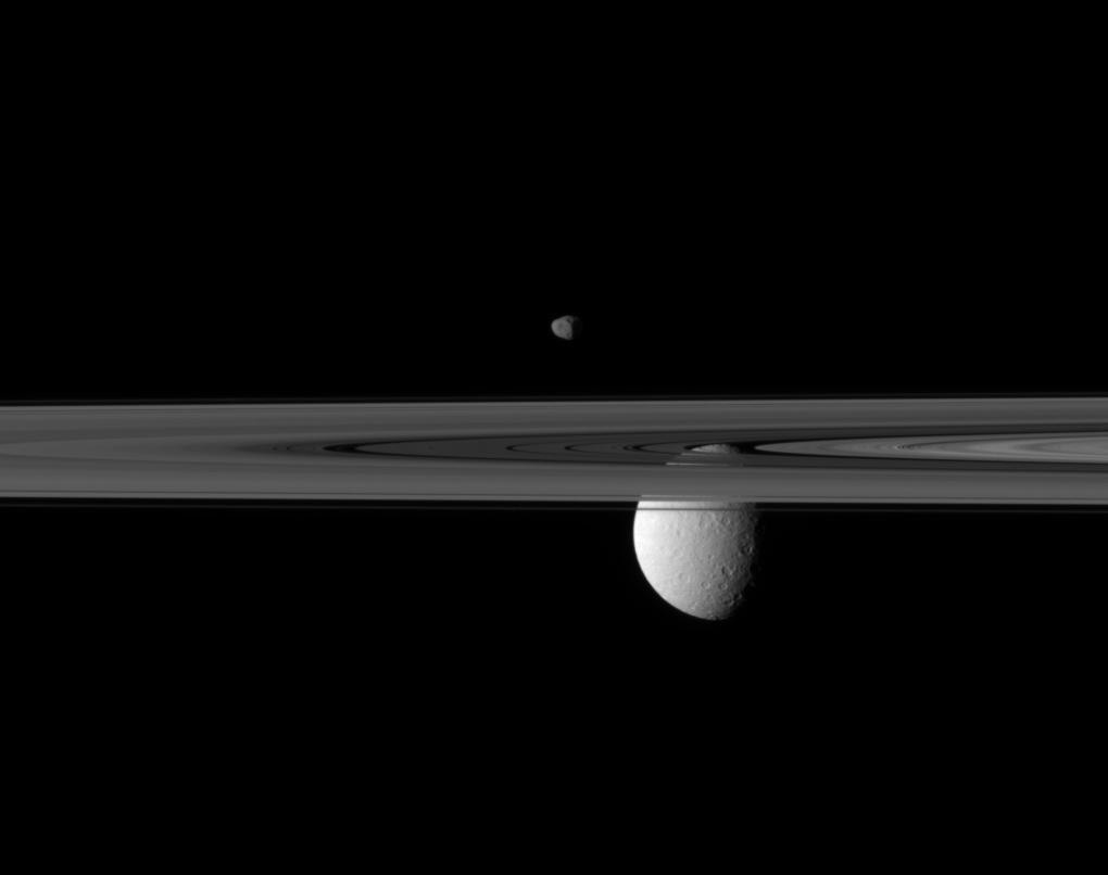 Кольца Сатурна, а также спутники Янус (вверху) и Рея.